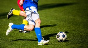 Zwei Fußballspieler kämpfen um den Ball, zu sehen sind nur die Beine.