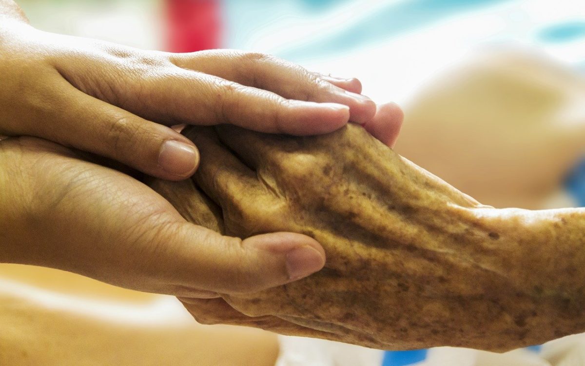 Jüngere Hände halten eine ältere.
